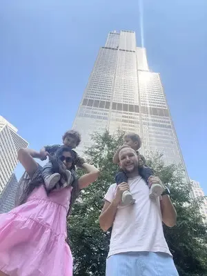 Salomón con uno de sus hijos en hombros, frente a una torre en Chicago