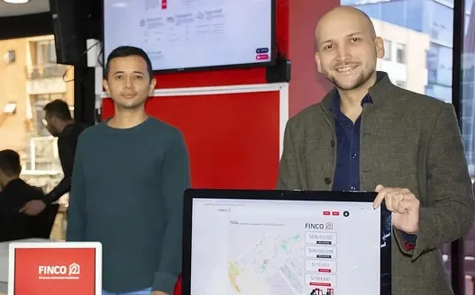 Salomón Muriel mostrando la plataforma de Finco en una feria, junto a un compañero de equipo